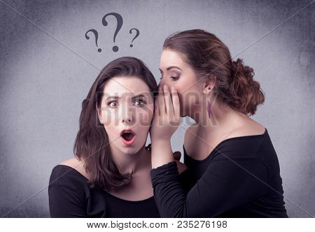 A teenager girl looking confused with drawn question marks above the head, while a girlfriend whispers something in her ear concept.