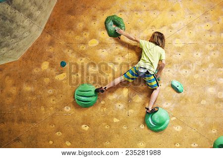 Boy Climber Climbs Indoors In Bouldering Gym