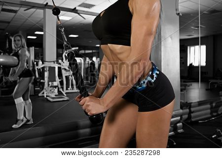 Female doing exercise on triceps with pulldown station