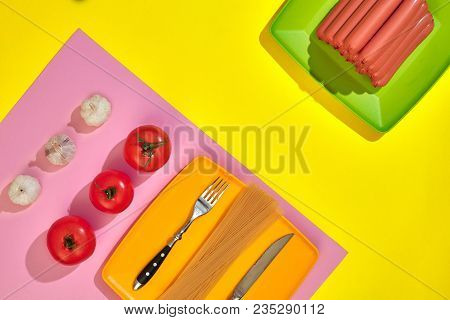A Lot Of Raw Sausages On Plate. On Yellow Background With Pasta And Vegetables, Top View. Still Life