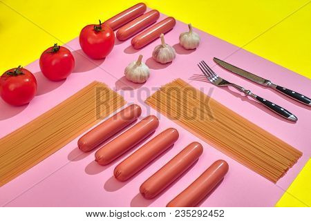 A Lot Of Raw Sausages With Pasta And Vegetables On Pink And Yellow Background, Top View. Still Life.