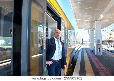 Portrait Of The Train Conductor Middle Aged Waiting Passengers To Board. Modern Train At The Europea