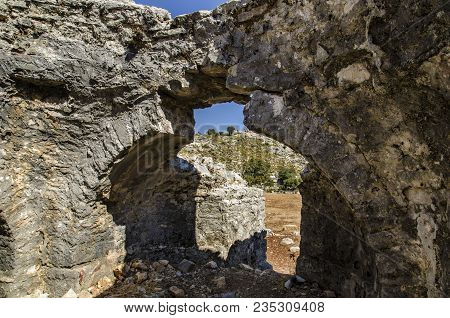 Ruins Of The Ancient City Of Sidima, Turkey, A Wall With A Partially Preserved Arch Against A Blue S