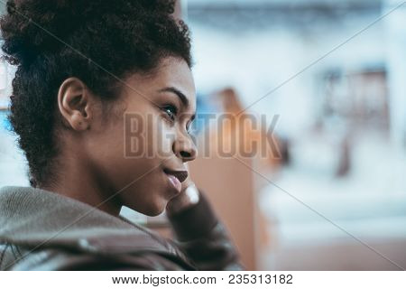 Close-up Side View Of A Young Cute Brazilian Girl With A Curly Afro Hair And In A Dark-green Light O