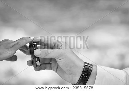Hands Of Groom Puts Keyless Entry System On Chain On Bride Finger During Wedding Ceremony On Natural