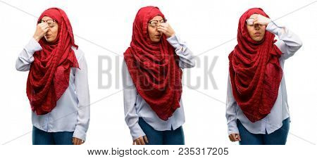 Arab woman wearing hijab with sleepy expression, being overworked and tired, rubbes nose because of weariness isolated over white background