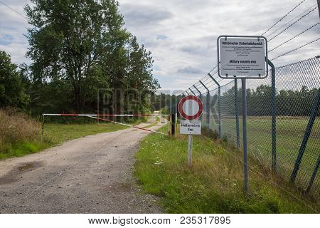 Photograph Of A Military Zone With Barbed Wire, Gate And Warning Signs.