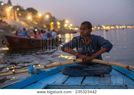 VARANASI, INDIA - MAR 13, 2018: Boatmen on the Ganga river at night. Varanasi is one of the most important pilgrimage sites in India and is one of the 7 sacred cities of Hinduism.