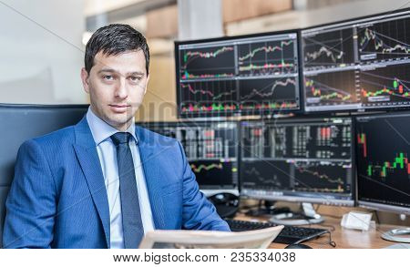Business Portrait Of Confident Stocks Broker Holding A Business Newspaper In Traiding Office With Mu
