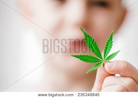 Smiling Kid Child Holding A Hemp Leaf. Concepts Of Using Marihuna For Medicinal Purposes For Childre