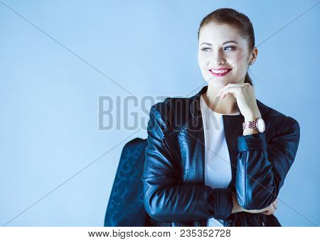 portrait of beautiful young brunette woman in stylish black jacket on gray.