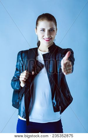 portrait of beautiful young brunette woman in stylish black jacket on gray.