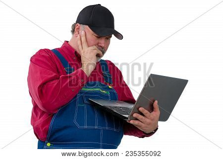 Farmer Standing Reading A Handheld Laptop Computer With His Hand To His Face And An Engrossed Expres