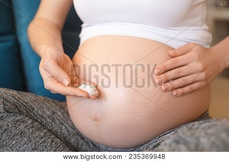 Closeup Pregnant Woman Applying Moisturizing Cream At Her Belly For Prevention Of Stretch Marks. Pre