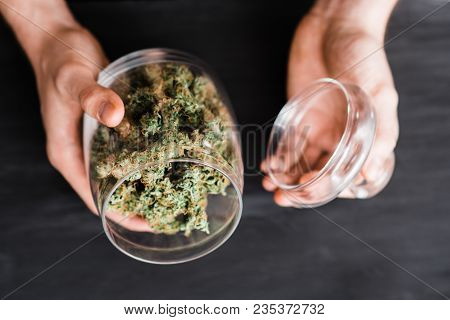 A Can With Buds Of Cannabis In The Hands Of A Man. The Concept Of Legal Marijuana Is Medical Weed. O