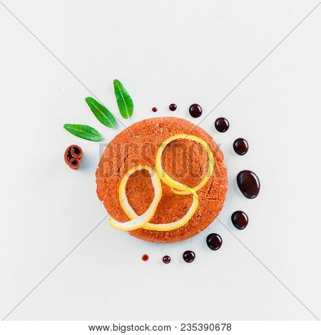 Cookie Decorated With Lemon Zest, Chocolate Drops And Green Leaves On A White Background. Pastry Sty