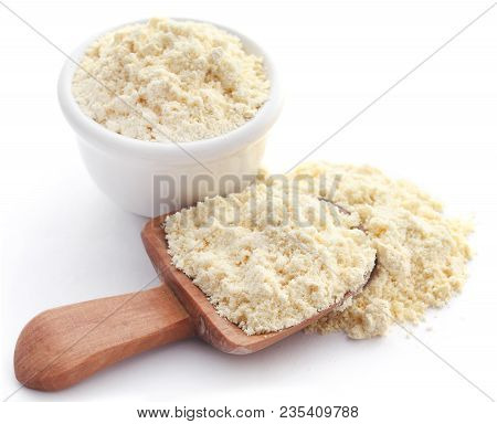 Gram Flour In Bowl And Wooden Scoop Over White Background