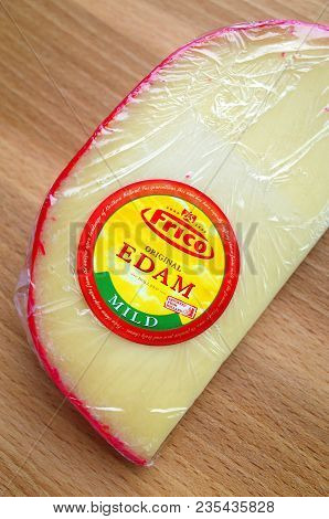 Bracknell, England - April 10, 2018: Part View Of A Wedge Of Edam Cheese Wrapped In Cling Film On A 