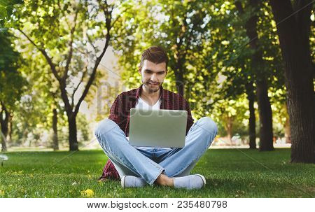 Handsome Young Man Using A Laptop Outdoors. Student Focused On Studyin With Laptop In Pleasant Atmos