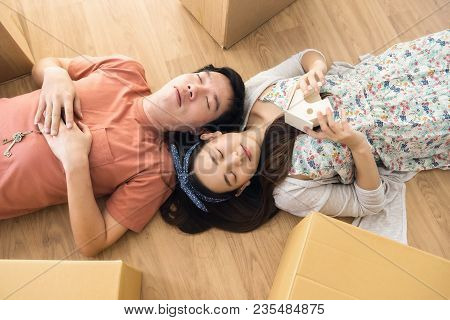 Tired Couple Sleep On Empty Room Of New House
