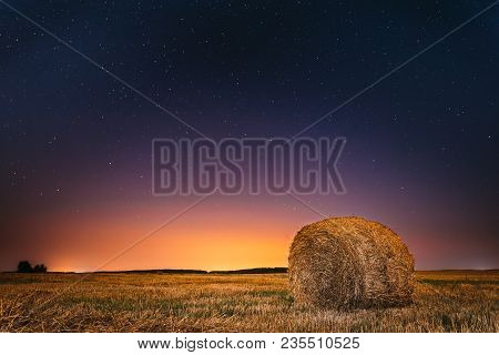 Natural Night Starry Sky Above Field Meadow With Hay Bale After Harvest. Glowing Stars And Sunset Su