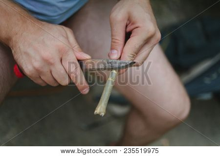 Man On Rest With A Knife Cuts Out Of A Tree A Peg For A Tent