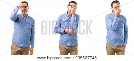 Middle age handsome man with sleepy expression, being overworked and tired, rubbes nose because of weariness over white background