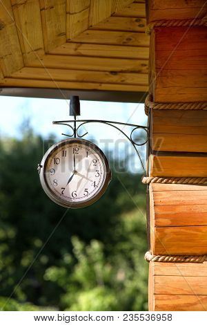Antique Outodoor Clock Hanging Outside A Wooden House Made Of Logs ..