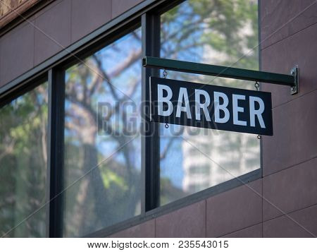 Modern Barber Sign Hanging Outside The Shop In An Urban Environment