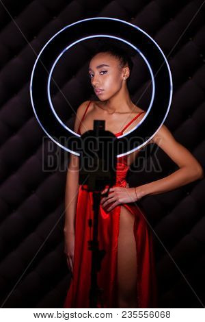 Portrait young african woman with ring flash effect. Round LED Circle Lamp in dark studio