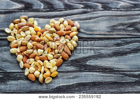 Mix Nuts In A Pottery On A Wooden Background In The Form Of A Heart.
