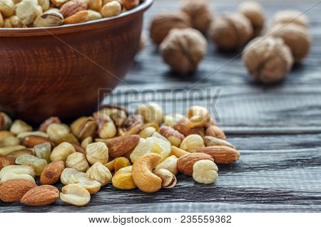 Mix Nuts In Earthenware On A Wooden Background.