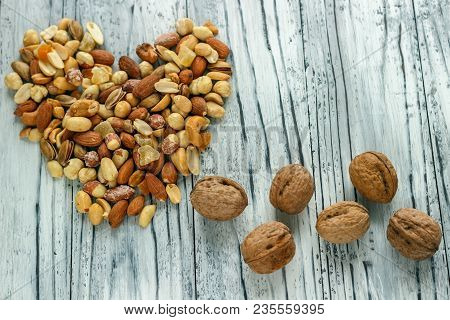 Mix Nuts In A Pottery On A Wooden Background In The Form Of A Heart.