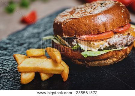 Burger With Cheese And French Fries Or Chips On Darj Stine Table