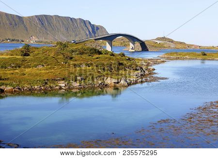 Panoramic View Of Famous Fredvang Bridges In Autumn Sunny Evening With Mountains In Backgrond And Be