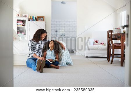 Mother and daughter reading a book in girl's room