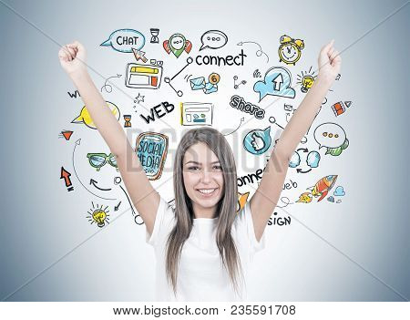 Smiling Young Woman With Brown Hair Wearing A White T Shirt Is Standing With Her Hands In The Air An