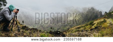 Panoramic Shot Of Traveler Making Photo Of Amazing Steep Mountainous Terrain With Lush Canyon Valley