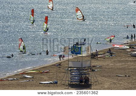 The Beach On The Mediterranean Sea With The Tourists And The Windsurfers Riding On The Cape Prasonis