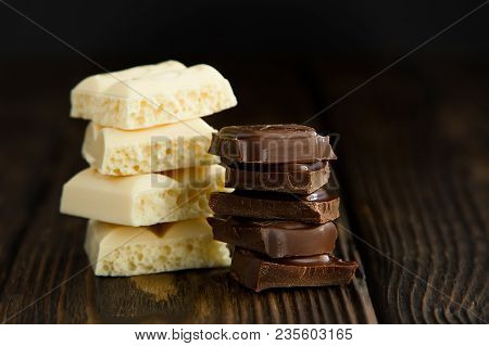 Pyramids Of Tasty White And Dark Chocolate Pieces On Wooden Dark Background In Moodle Style