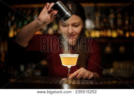 Female Bartender Serving A Fresh Yellow Cocktail And Pouring A Spice Into It On The Bar Counter