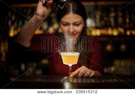 Smiling Female Bartender Serving A Fresh Delicious Yellow Cocktail And Pouring A Spice Into It On Th