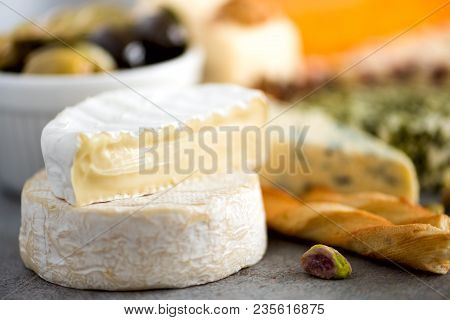 Assortment Of Hard, Semi-soft And Soft Cheeses With Olives, Grissini Bread Sticks, Capers, Grape, On
