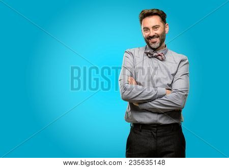 Middle age man, with beard and bow tie with crossed arms confident and happy with a big natural smile laughing