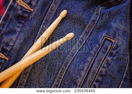 Two Drumsticks Lie On A Denim Jeans Textile