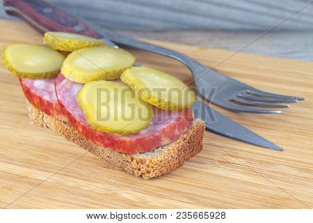 Marinated Cucumber Slices Of Sausage On A Piece Of Bread. On A Wooden Background.