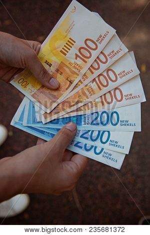 Woman Holding A Bunch Of Israeli New Sheqel Banknotes In Her Hands.