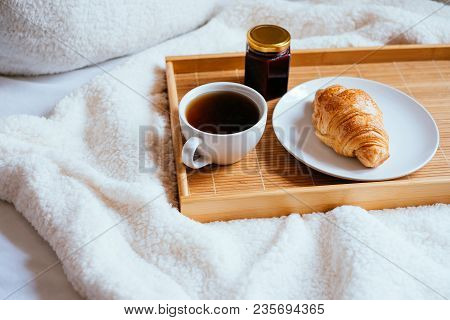 Big White Morning Cup Of Coffee, Crossant And Jam On The Wooden Tray In Bed With Pillow And Cosy Bla