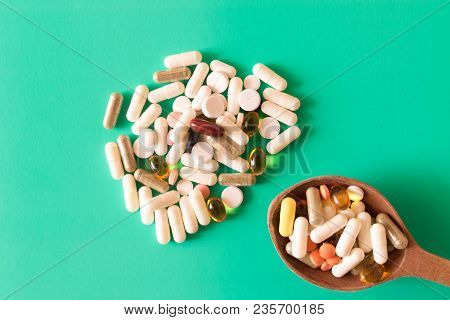 Many Colorful Pills With A Spoon On A Turquoise Background . The Concept Of A Healthy Lifestyle .