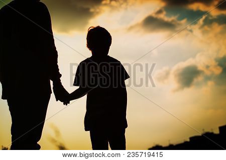 Silhouette Of Father And Son Holding Hands At Sunset Sky